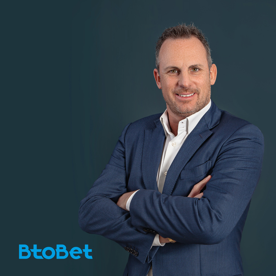 Alessandro Fried, man posing, arms corssed, BtoBet CEO, BtoBet logo on blue background