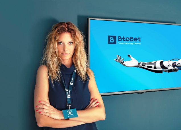 Sabrina Solda, CMO of BtoBet, Woman in blue background, arms crossed, btobet company logo